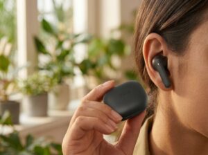 Detalhe ergonômico do fone de ouvido sem fio QCY T43 encaixado no ouvido e estojo de recarga USB-C em mãos.